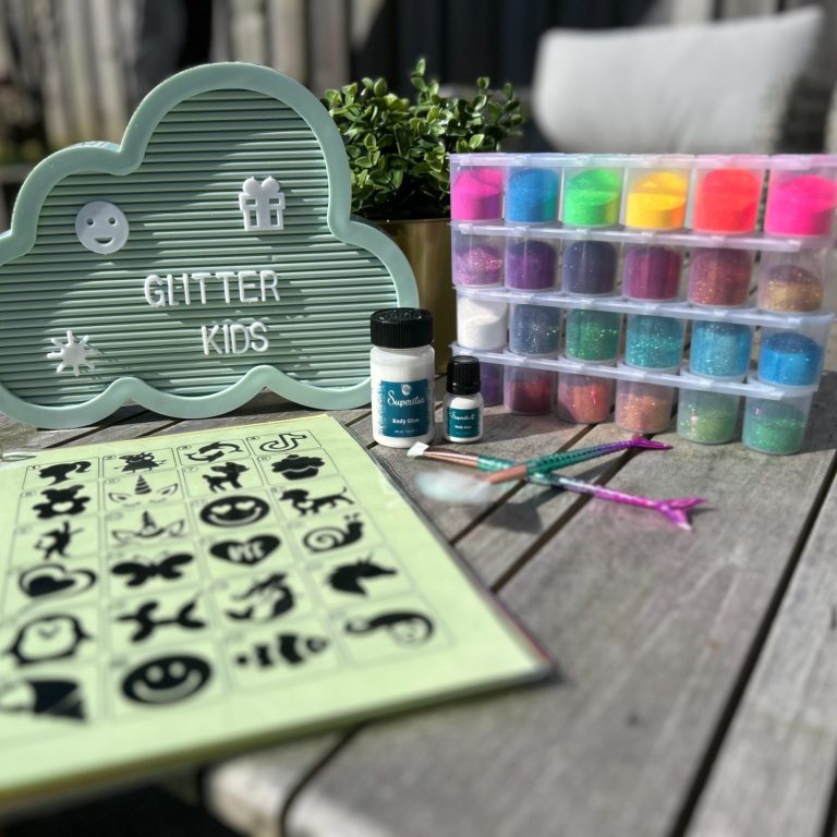 Knutselmaterialen met glitters, een kleurige opbergdoos en sjablonen op een houten tafel.